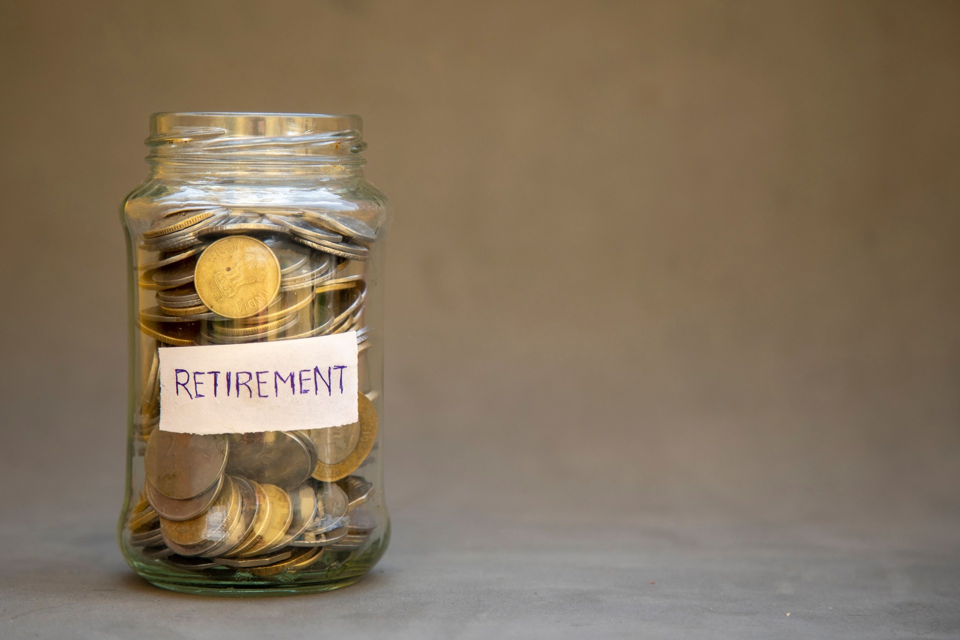 Glass Jar with Coins Labeled Retirement Suggesting Future Savings and Financial Planning.